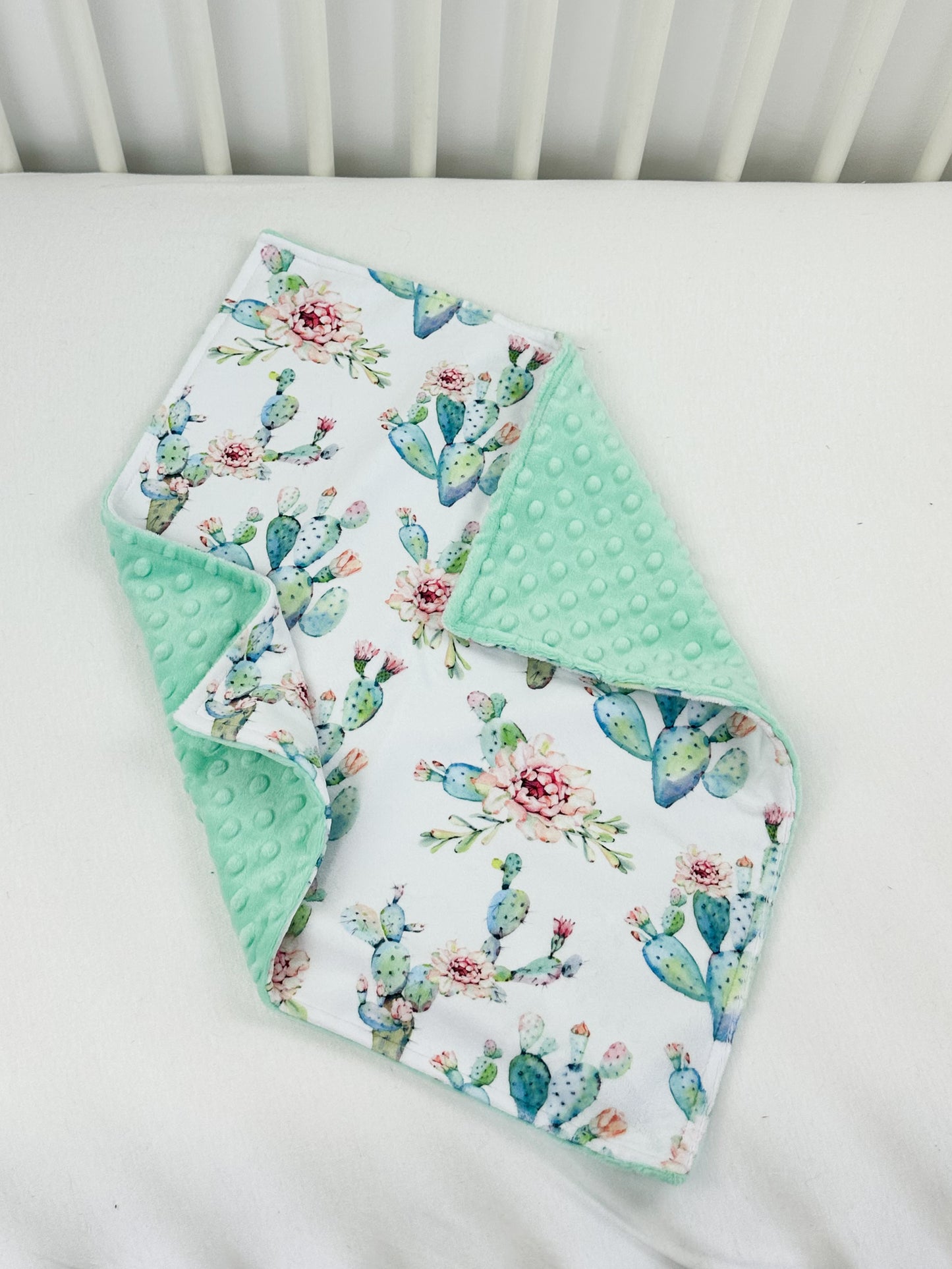a white crib with a green and white blanket