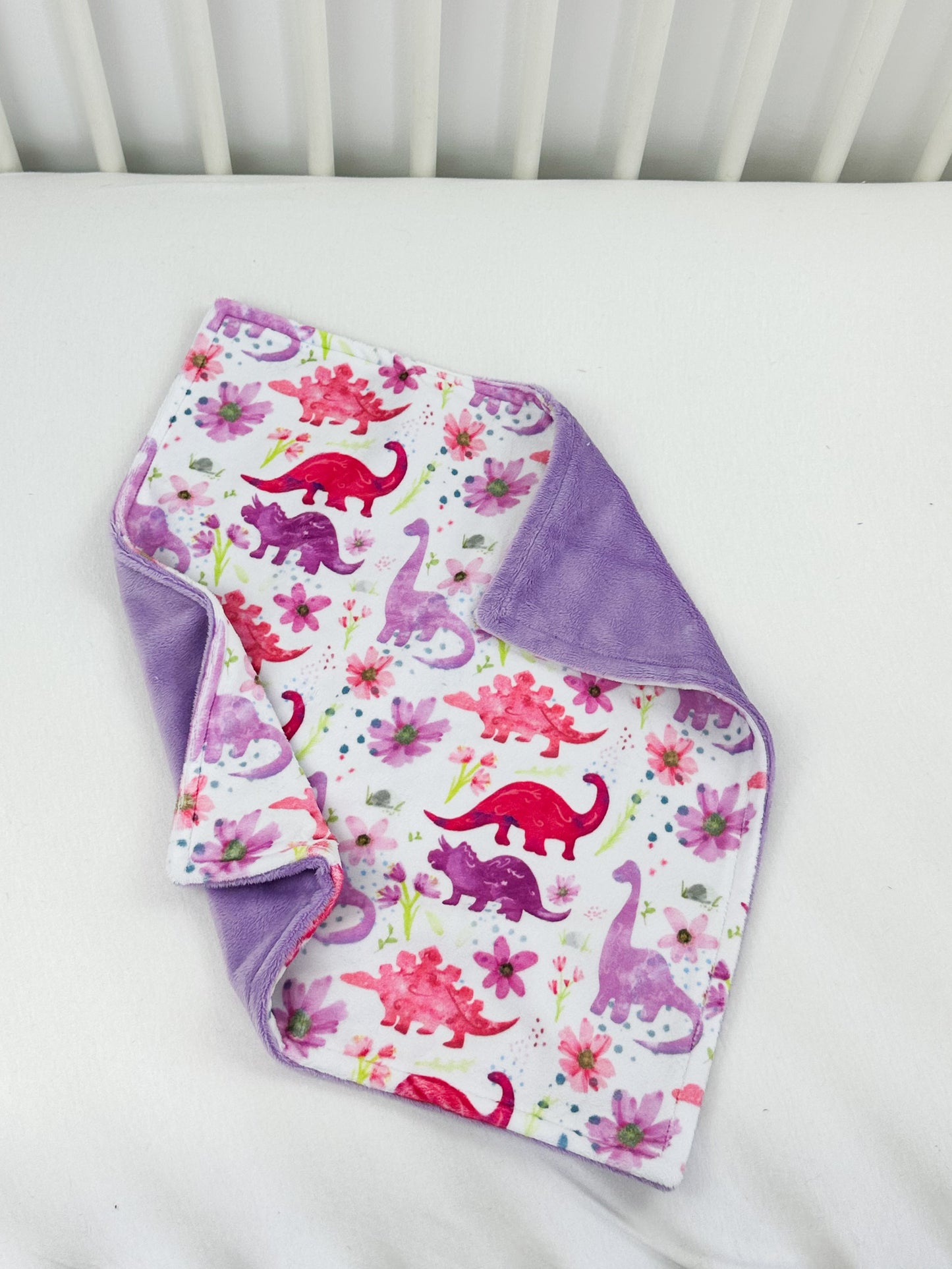 a baby's blanket and bib laying on top of a crib