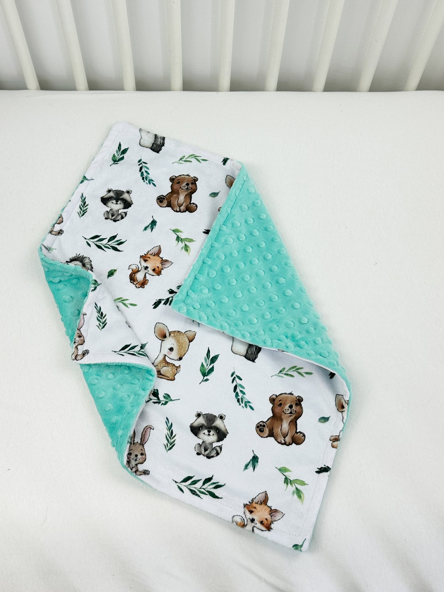 a crib bed with two bibs and a blanket