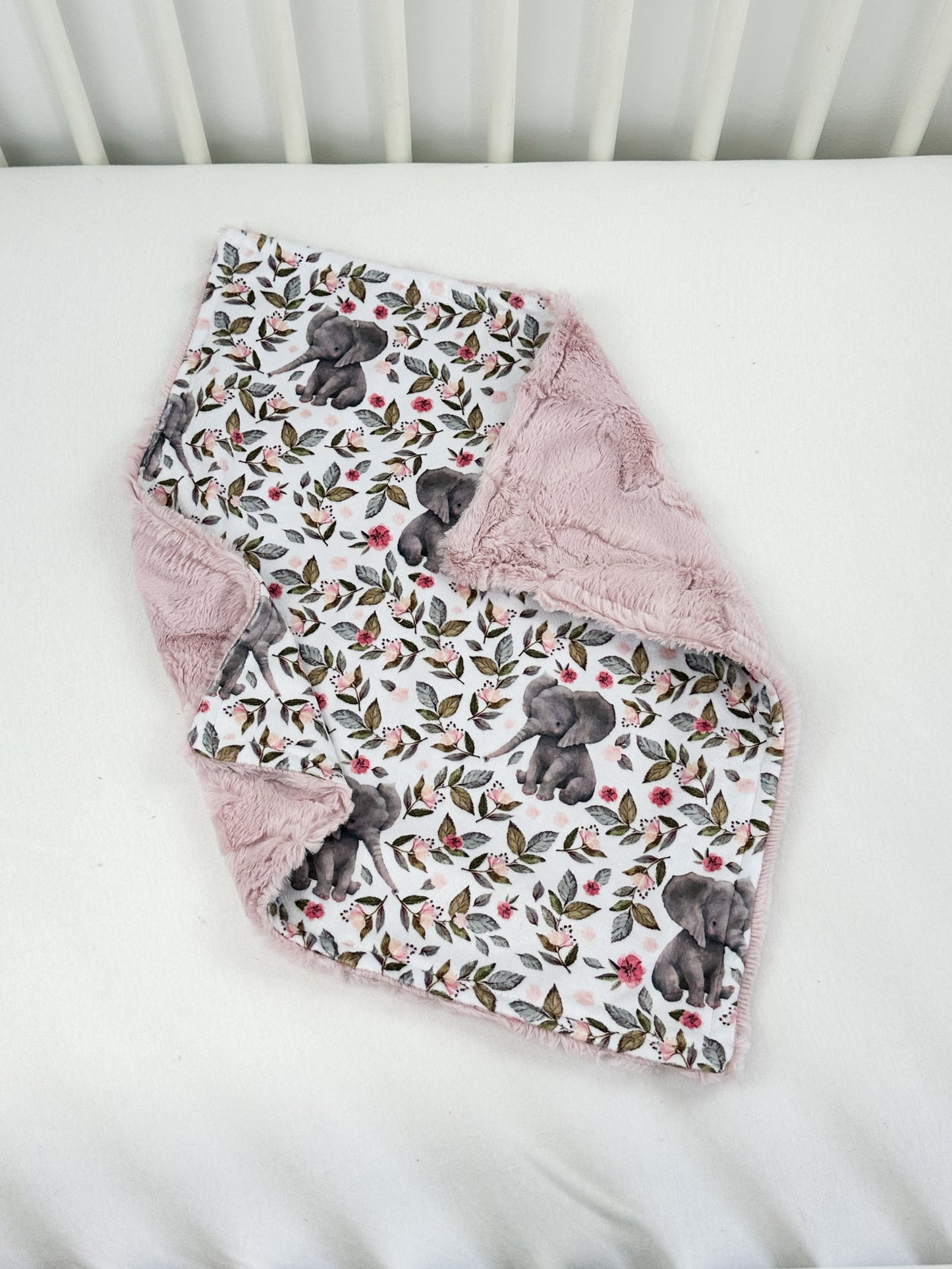 a white crib with a pink blanket on top of it
