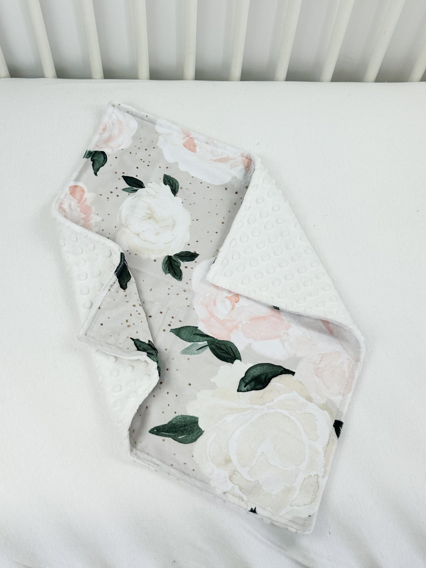 a white crib bed with a flowered blanket