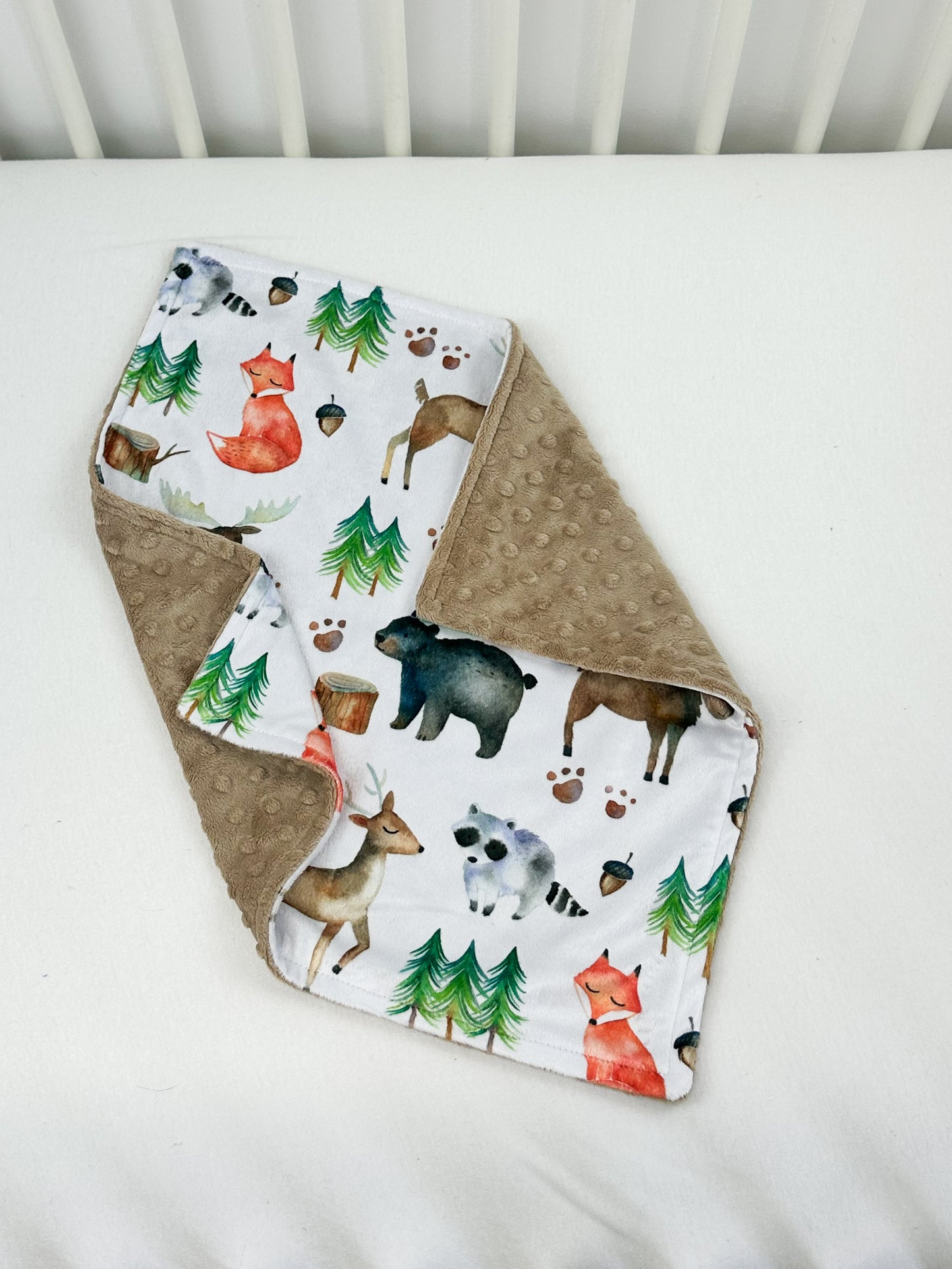 a baby bib with animals on it laying on a bed
