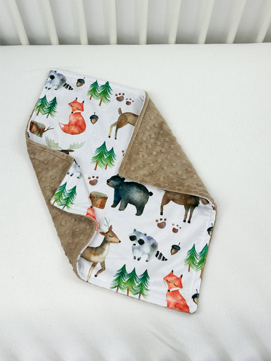 a baby bib with animals on it laying on a bed