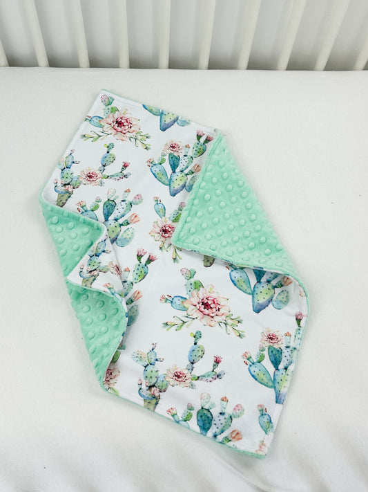 a white crib with a green and white blanket