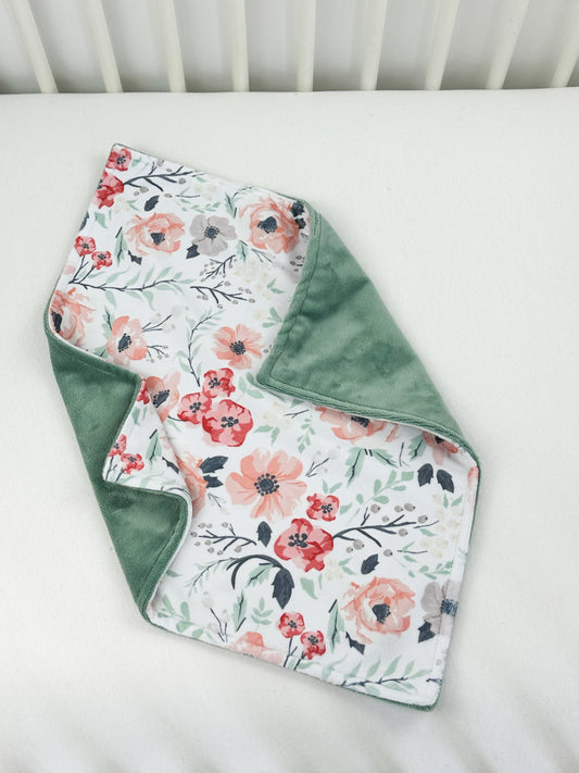 a white crib with a green blanket and a flowered blanket