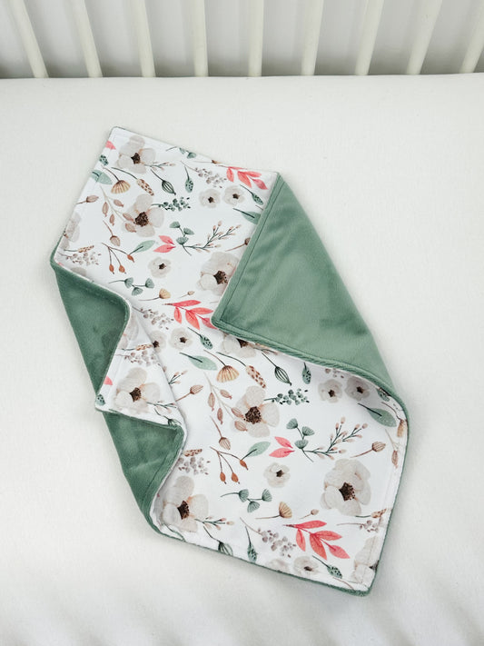 a white crib with a green and white blanket