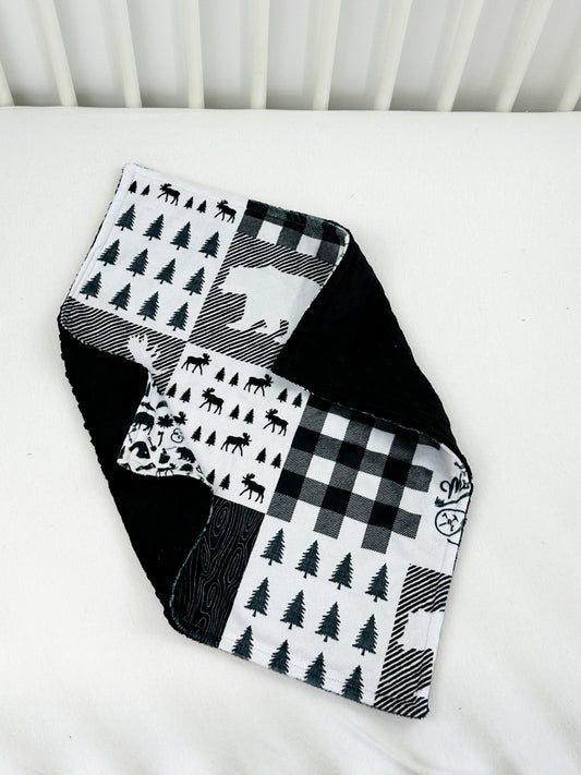 a black and white quilt on a white crib