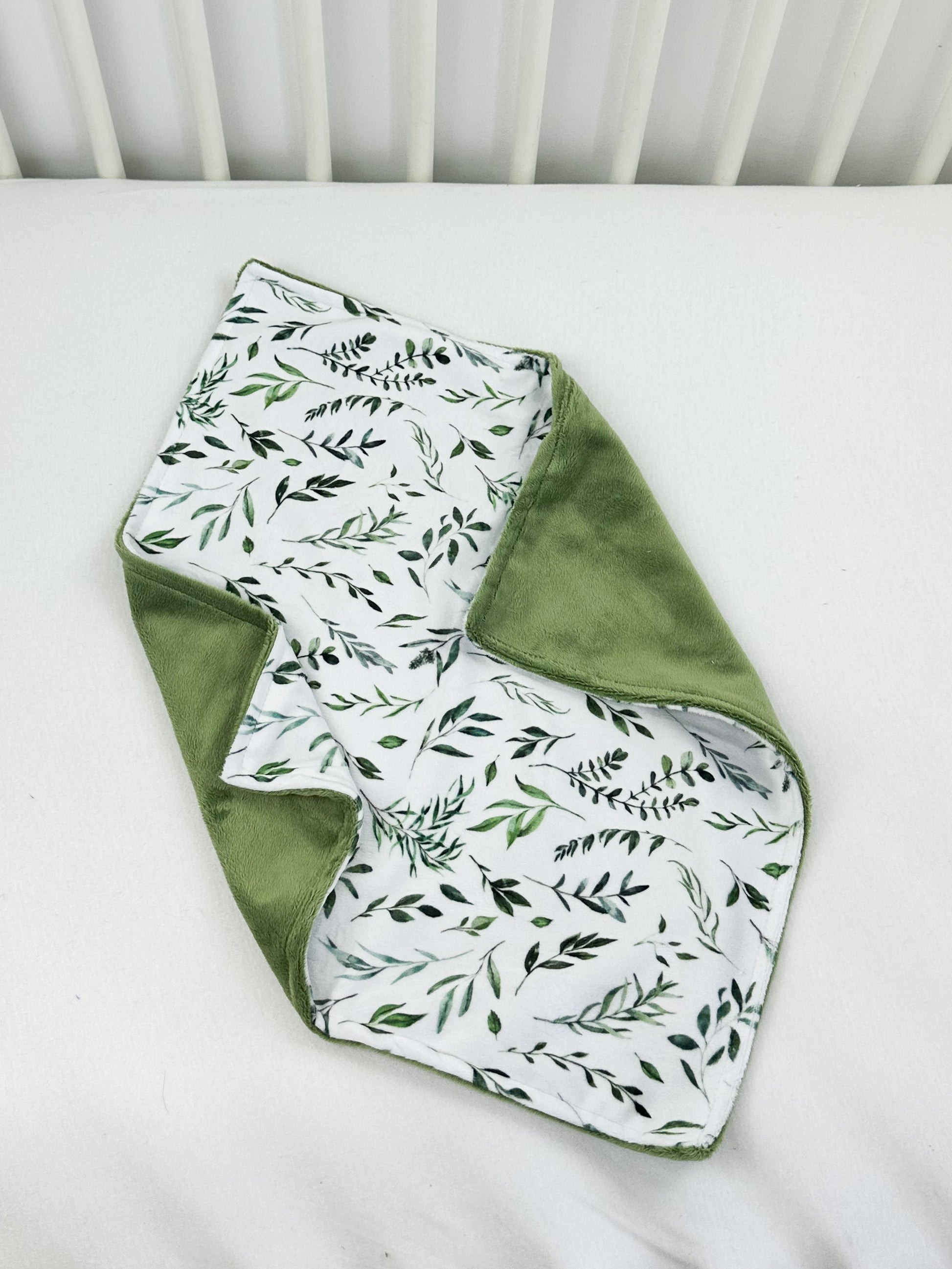 a white crib with green leaves on it