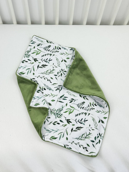 a white crib with green leaves on it
