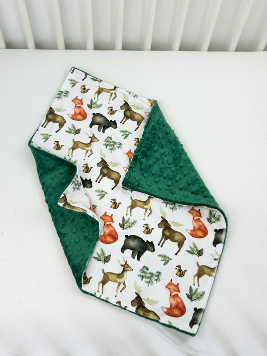 a green and white blanket with animals on it