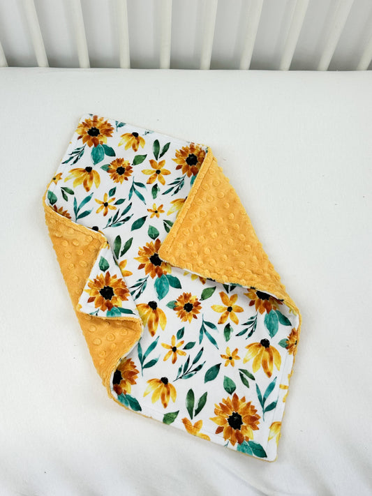 a yellow and white blanket with sunflowers on it