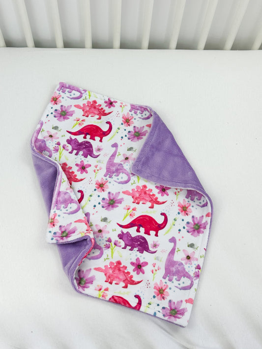 a baby's blanket and bib laying on top of a crib