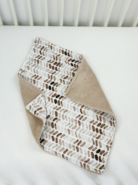 a white crib with a brown and white blanket on top of it