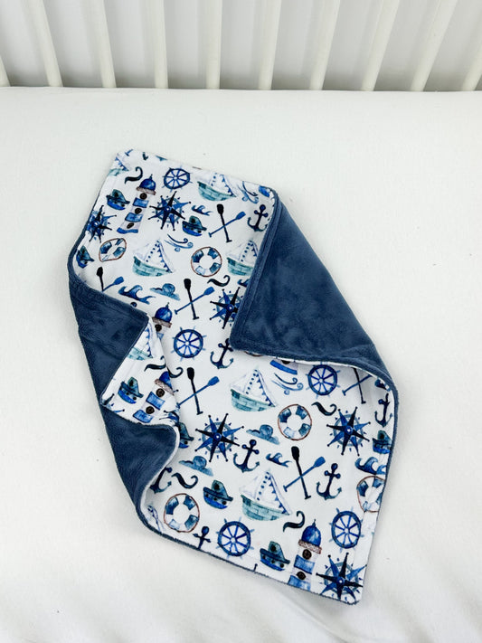 a blue and white bib laying on top of a bed