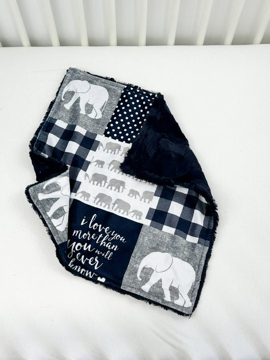 a baby crib with a black and white patchwork blanket