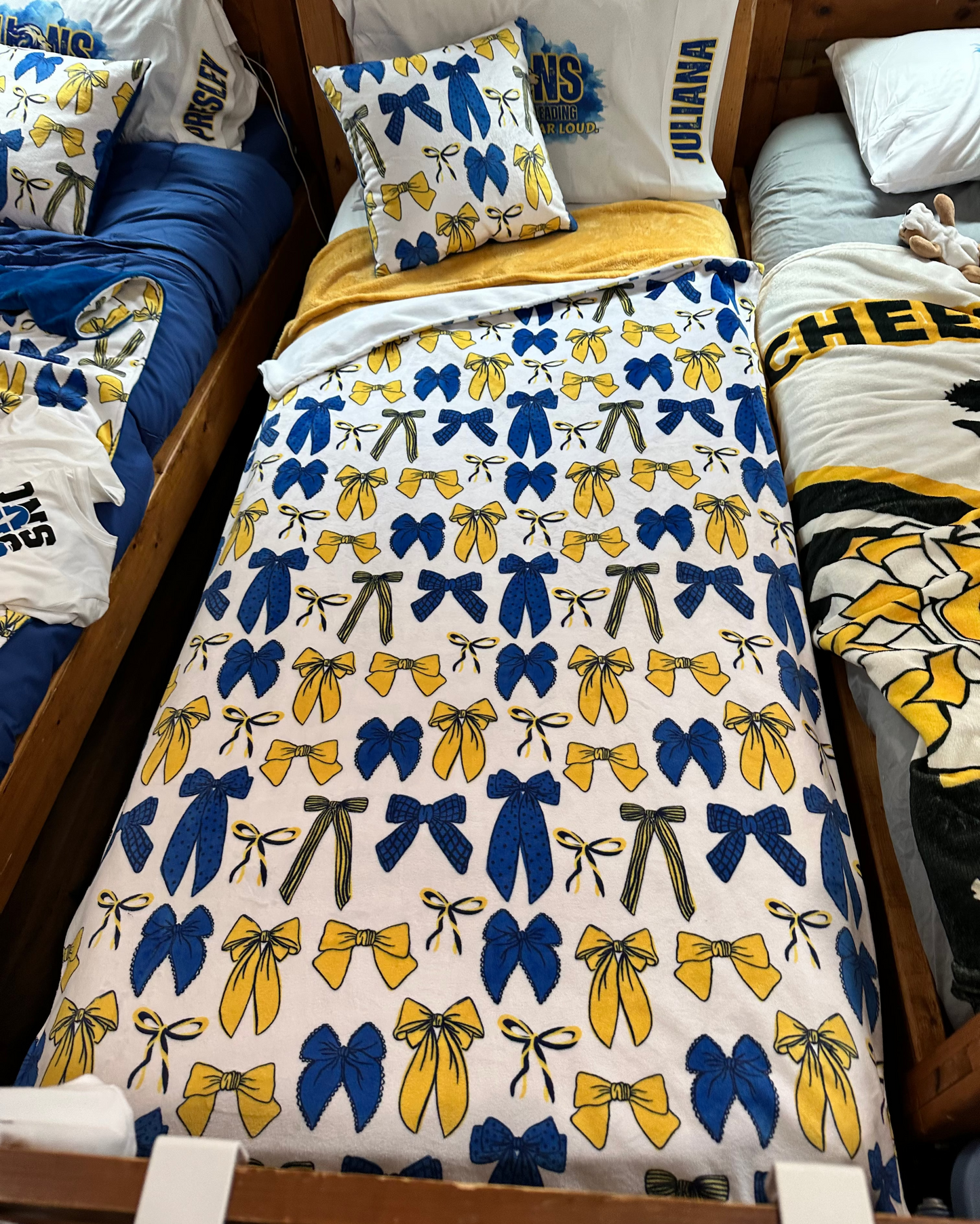 Bed with blue and yellow bow patterned comforter and various pillows.