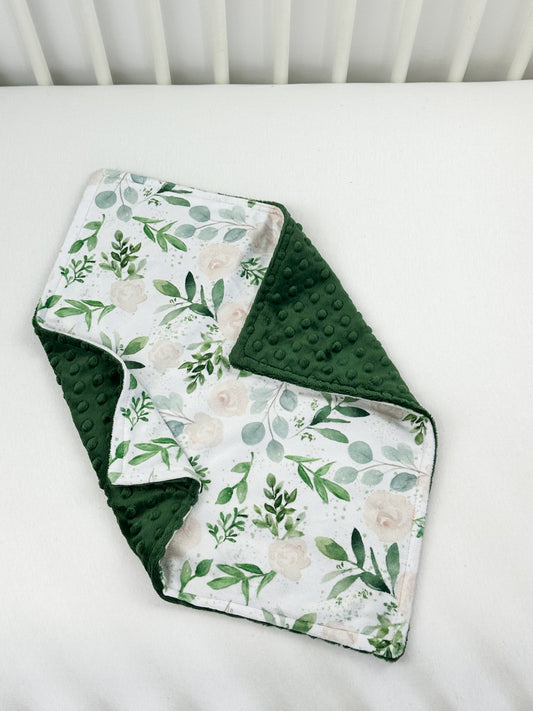 a white crib with a green and white blanket