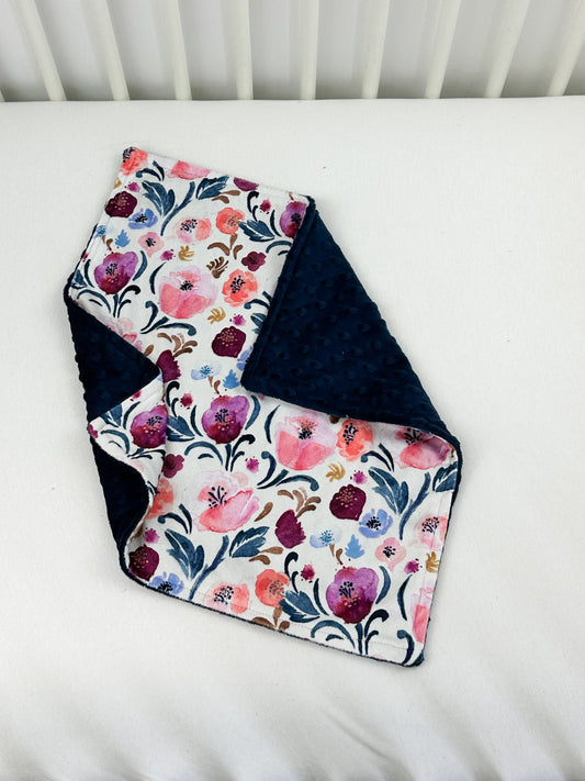 a white crib with a blue and pink blanket on it