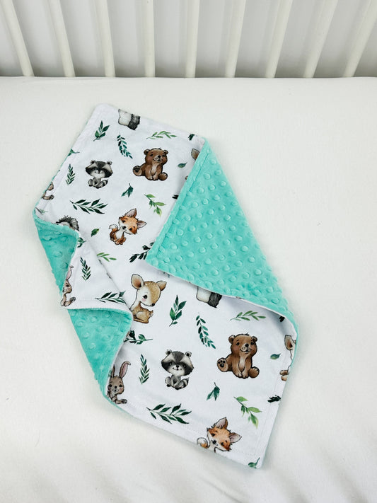 a crib bed with two bibs and a blanket