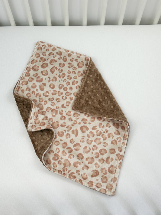 a white crib bed with a brown and white blanket