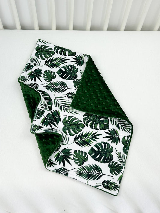 a white crib with green leaves on it