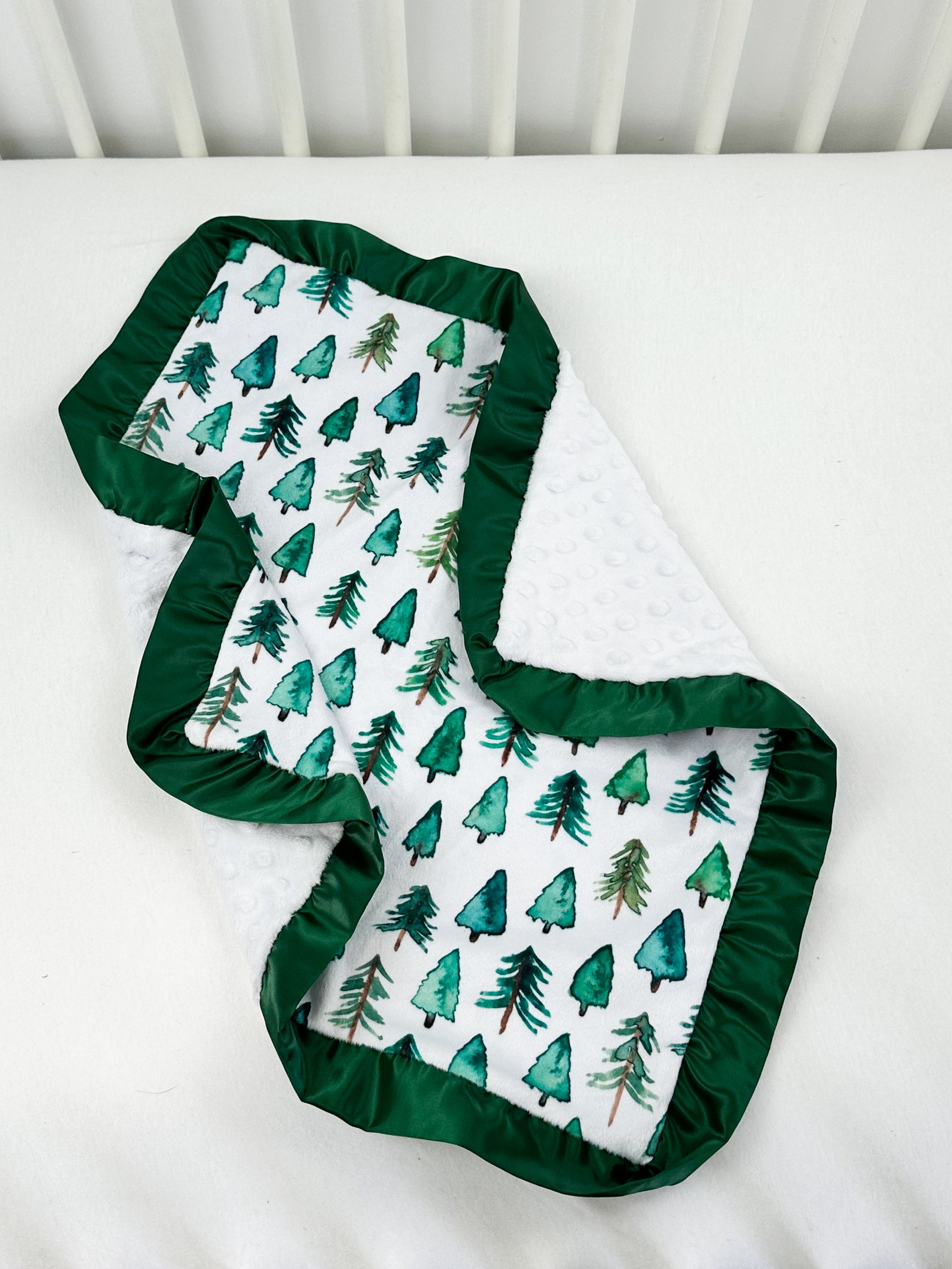 a baby's crib with a green and white blanket on top of it