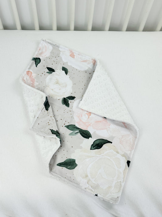 a white crib bed with a flowered blanket