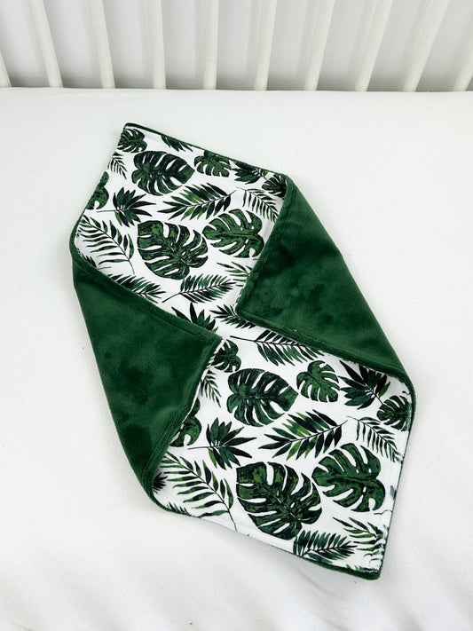 a green and white blanket on top of a white crib
