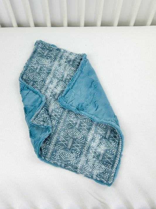 a baby's blue blanket laying on top of a white crib