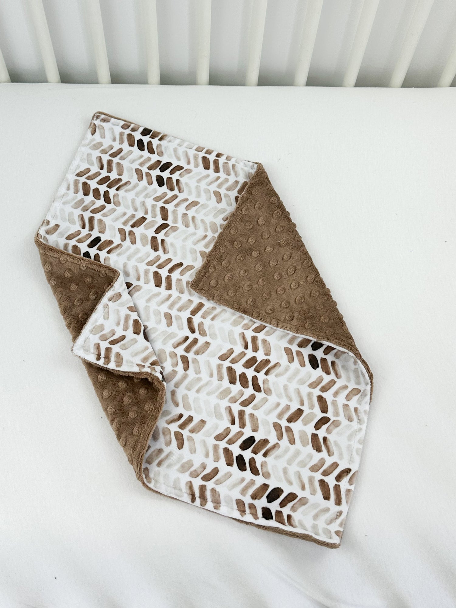 a white crib with a brown and white blanket